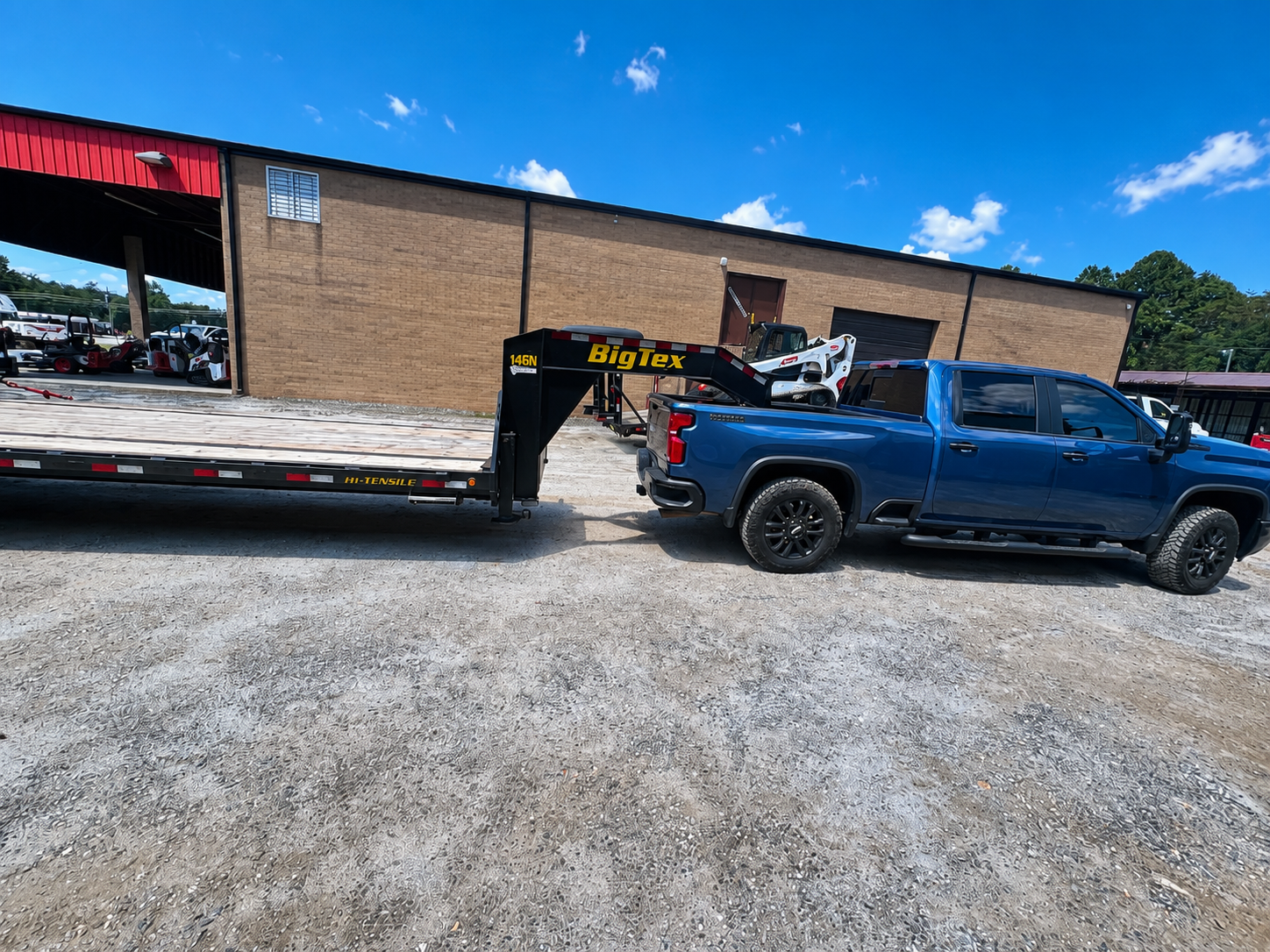 Blue pickup hitched to Big Tex gooseneck trailer at the yard